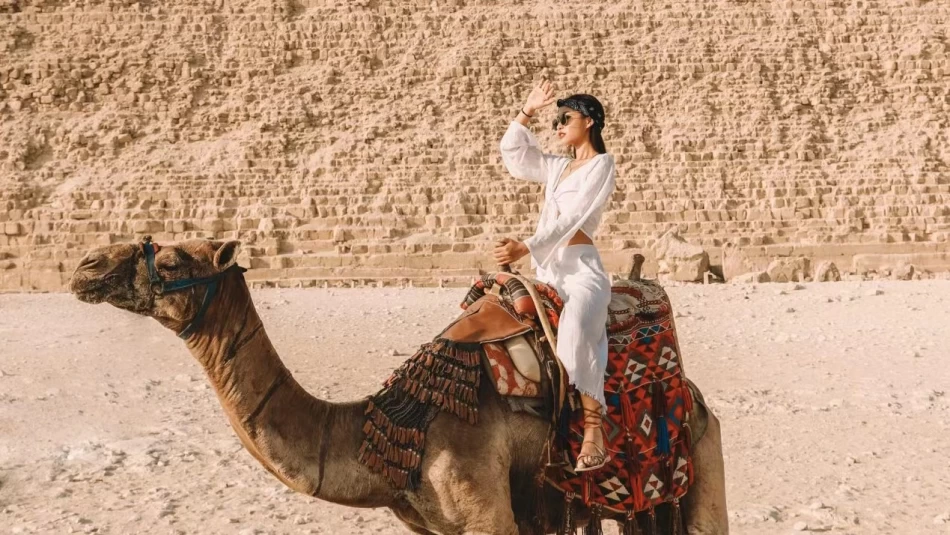 Tourists riding camels with the Great Pyramid of Giza in the background