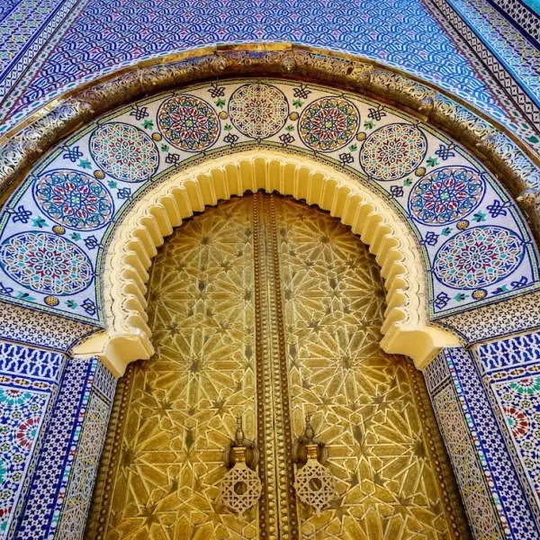 Interior of a Fes riad featuring intricate mosaic walls, and traditional Moroccan decor.