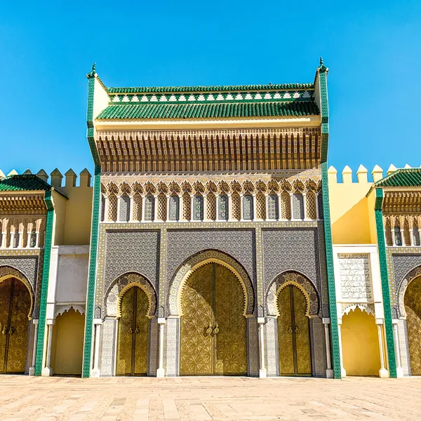 Exterior view of the Royal Palace of Marrakech with its iconic ochre walls and ornate brass doors