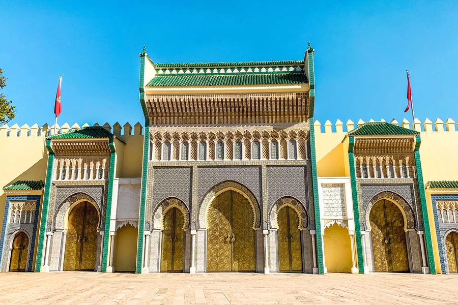 Exterior view of the Royal Palace of Marrakech with its iconic ochre walls and ornate brass doors