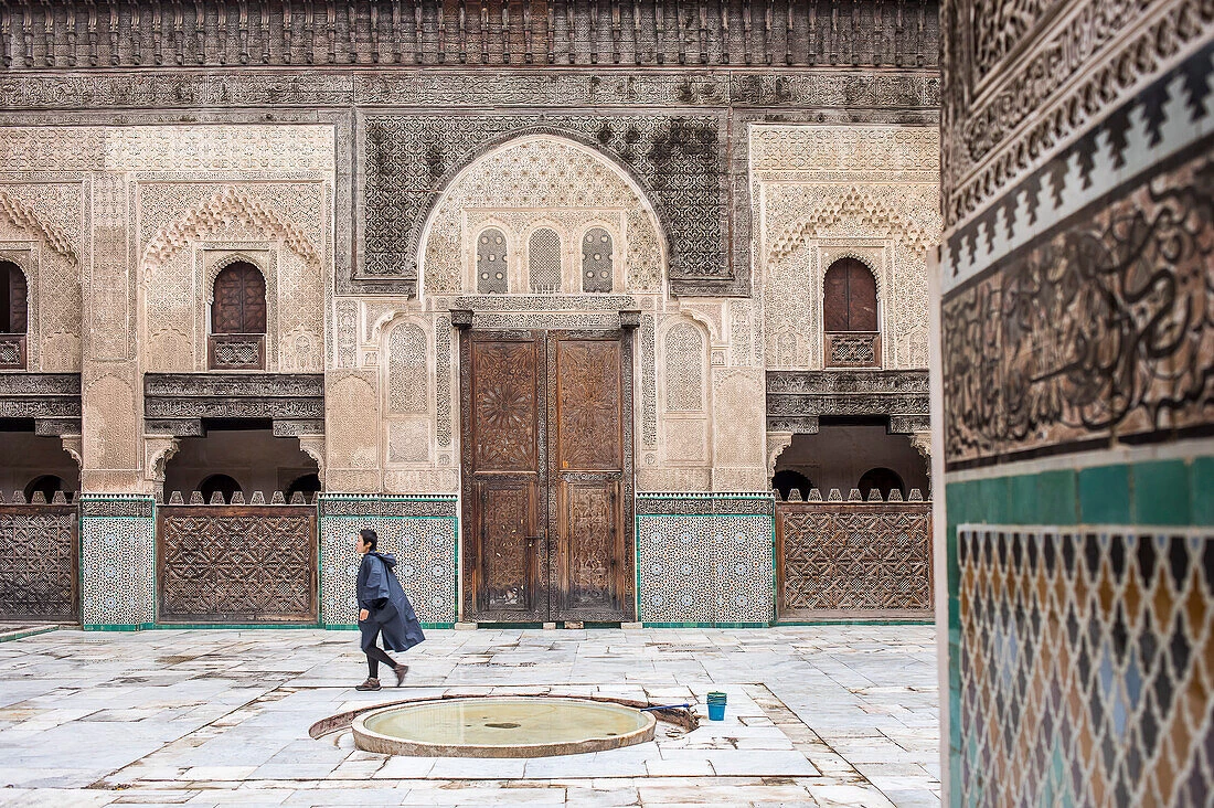 Courtyard of Bou Inania Madrasa in Meknes with zellige tiles, carved wood, and a central fountain