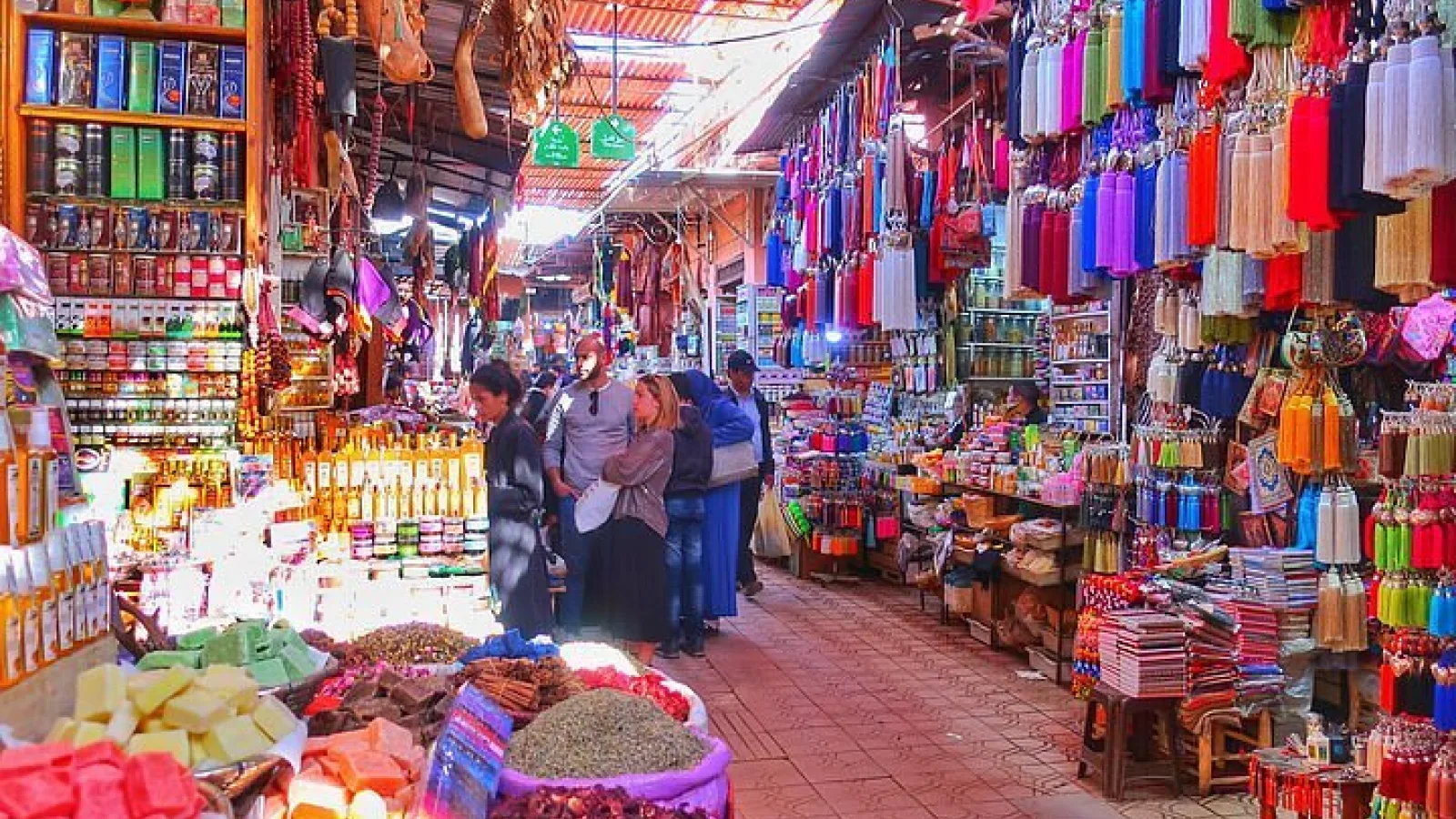 Visitors shopping in Souk Semmarine surrounded by Moroccan handicrafts and colorful goods